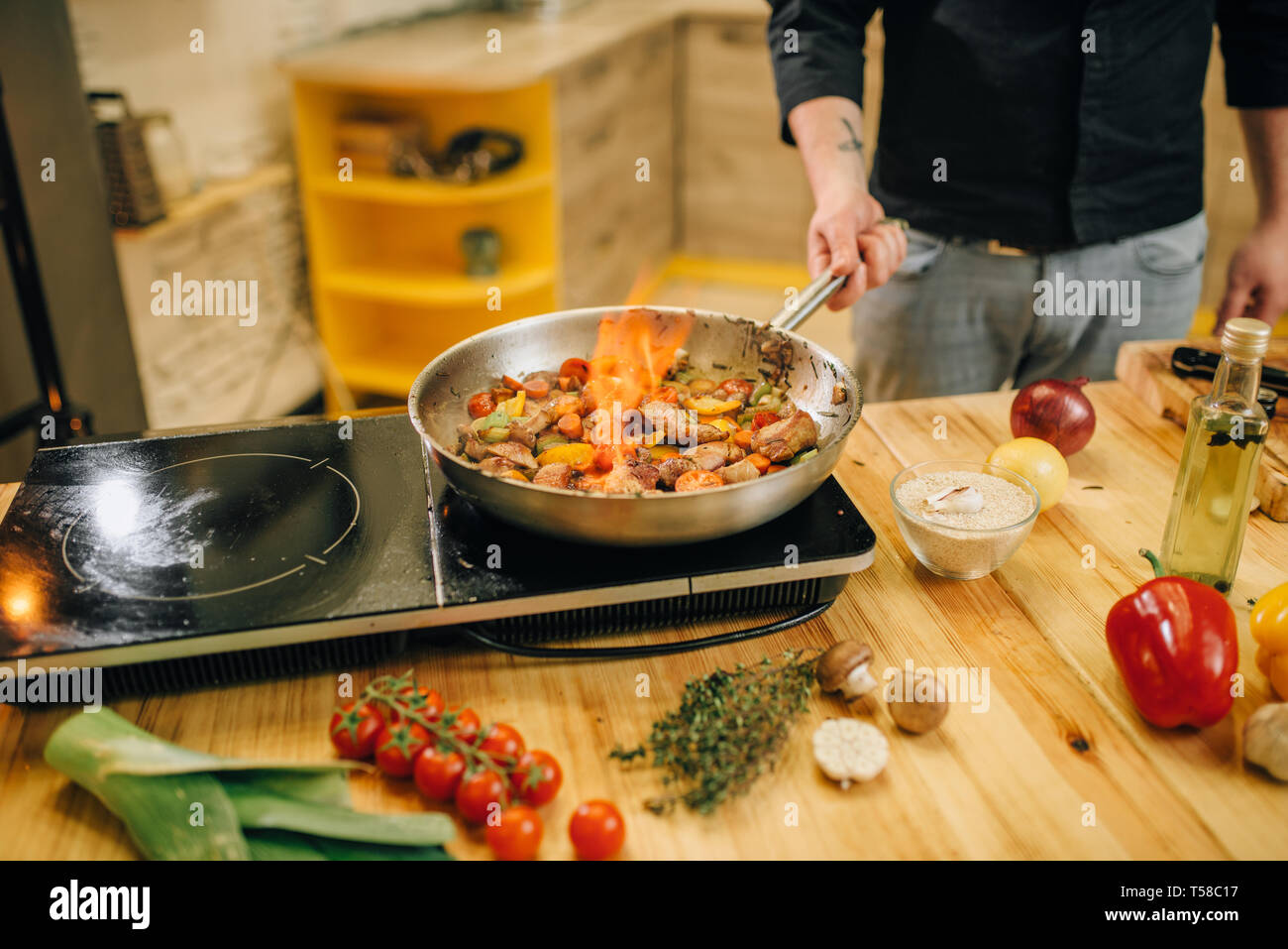 Male chef cooking meat avec vetables on fire Banque D'Images