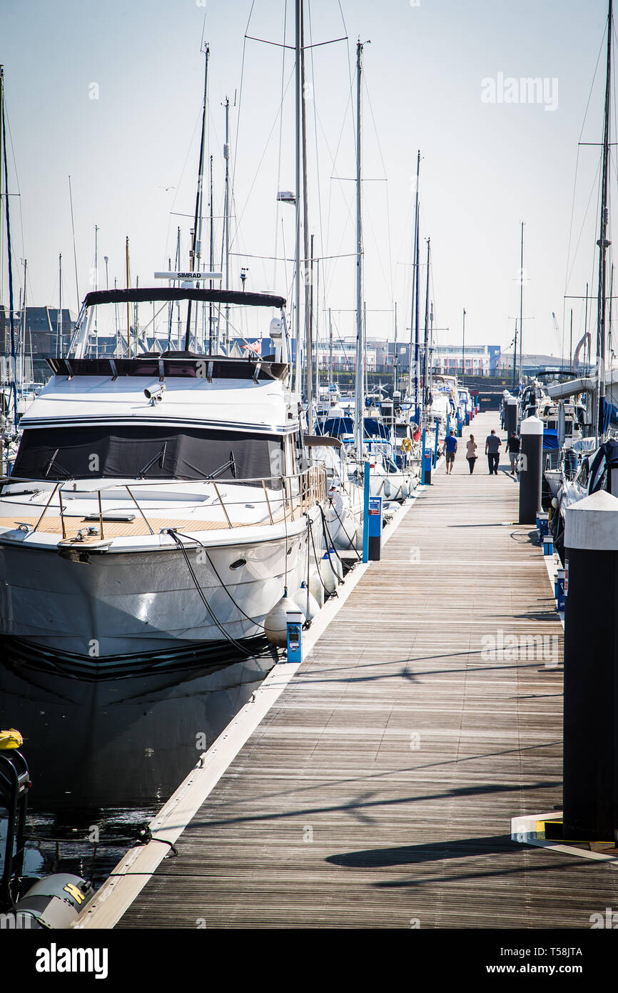 Port de Plaisance Maritime Chatham. Kent. UK. Les gens qui marchent sur un trottoir en cours des bateaux et yachts lors d'une journée ensoleillée. Banque D'Images