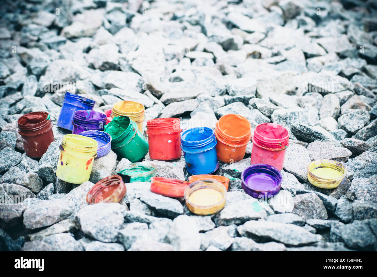 Petits pots de peinture dans le cadre de couleurs différentes sur les cailloux gris Banque D'Images
