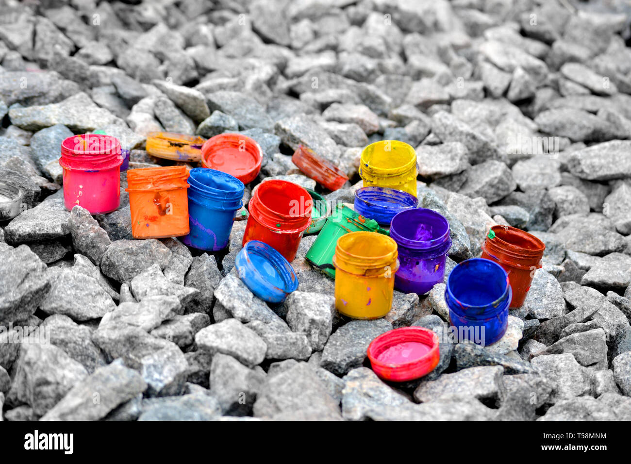 Petits pots de peinture dans le cadre de couleurs différentes sur les cailloux gris Banque D'Images