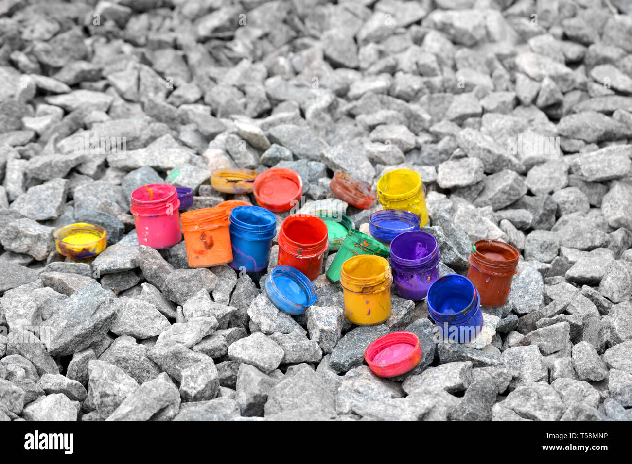 Petits pots de peinture dans le cadre de couleurs différentes sur les cailloux gris Banque D'Images