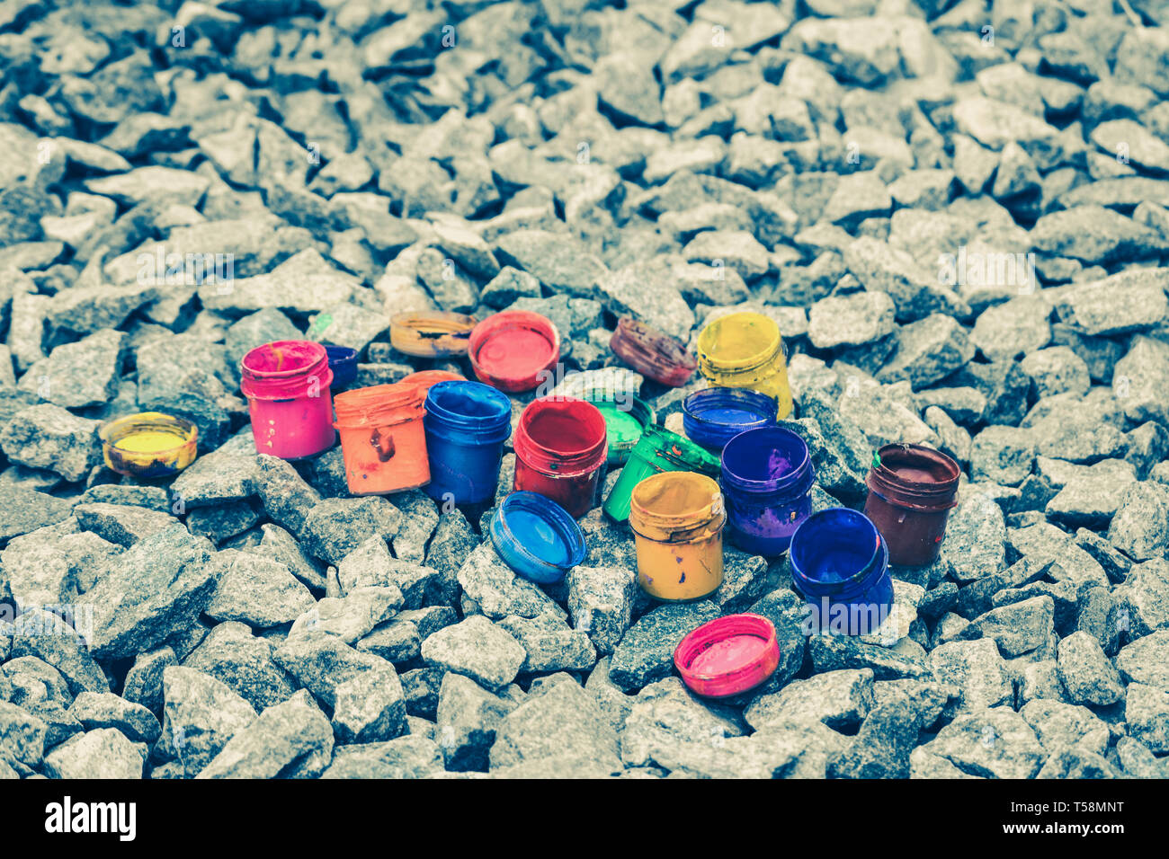 Petits pots de peinture dans le cadre de couleurs différentes sur les cailloux gris Banque D'Images