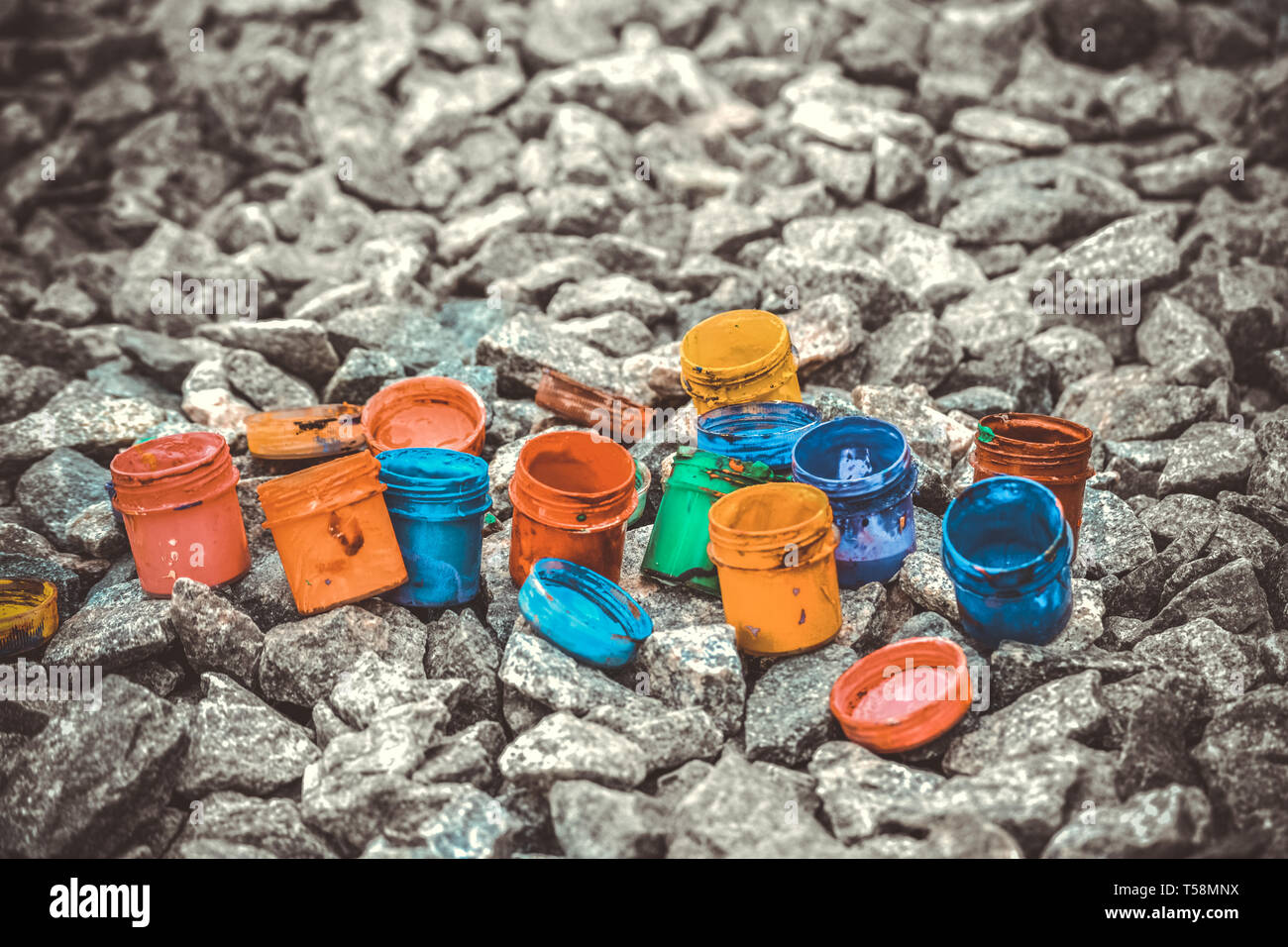 Petits pots de peinture dans le cadre de couleurs différentes sur les cailloux gris Banque D'Images