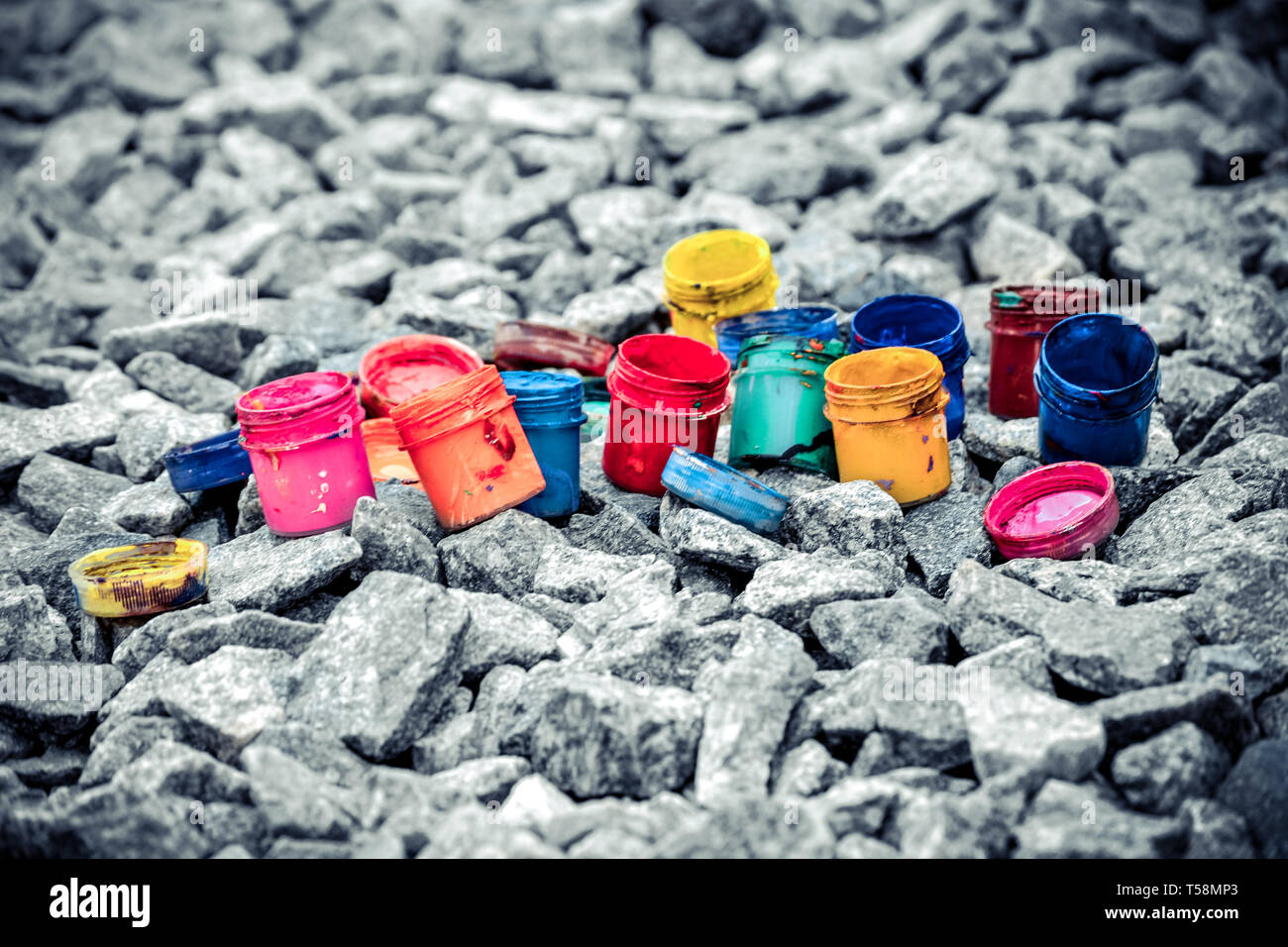Petits pots de peinture dans le cadre de couleurs différentes sur les cailloux gris Banque D'Images