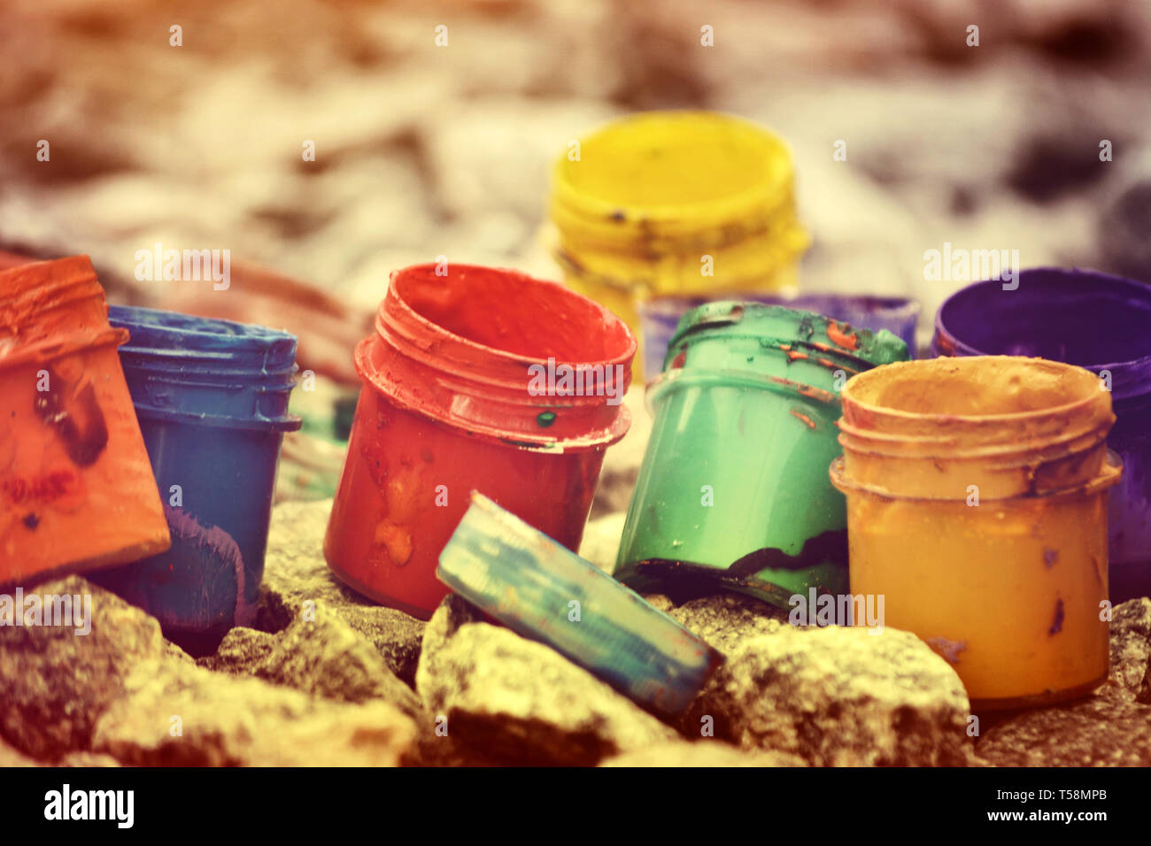 Petits pots de peinture dans le cadre de couleurs différentes sur les cailloux gris Banque D'Images