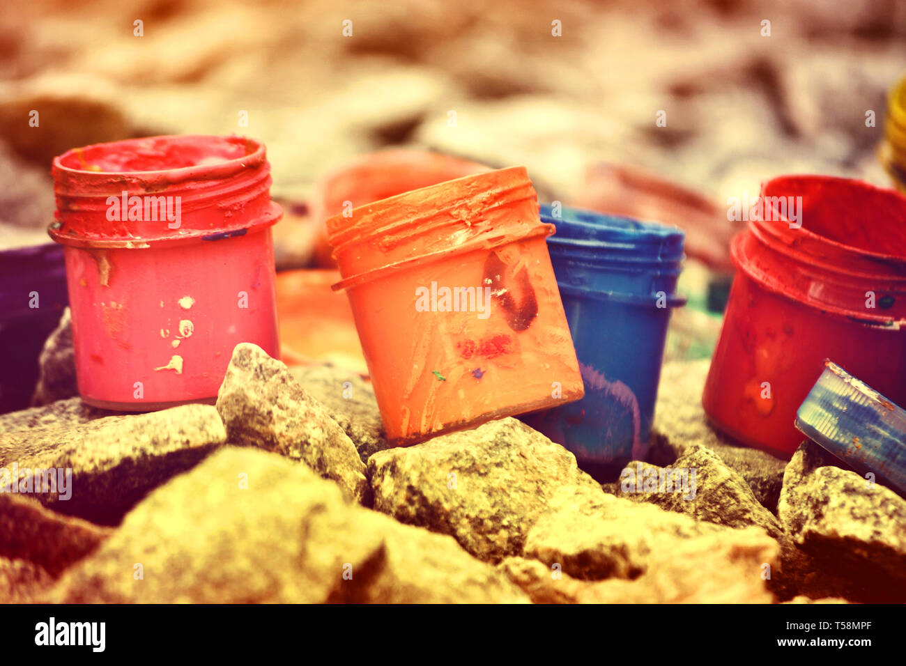 Petits pots de peinture dans le cadre de couleurs différentes sur les cailloux gris Banque D'Images