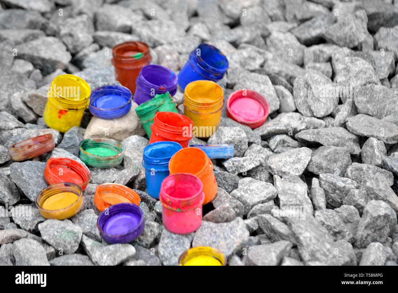 Petits pots de peinture dans le cadre de couleurs différentes sur les cailloux gris Banque D'Images