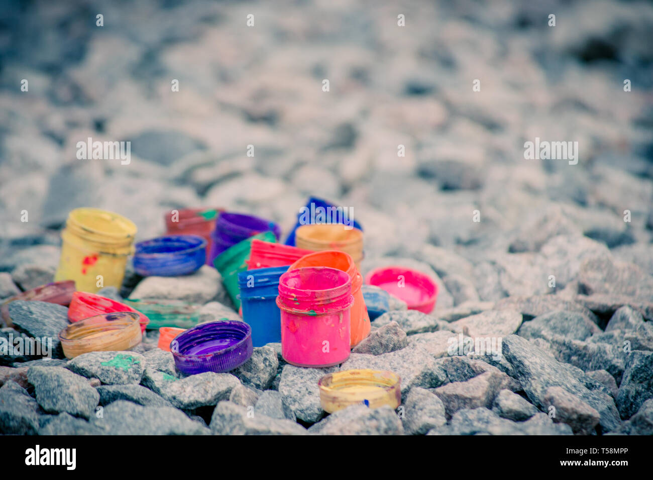 Petits pots de peinture dans le cadre de couleurs différentes sur les cailloux gris Banque D'Images