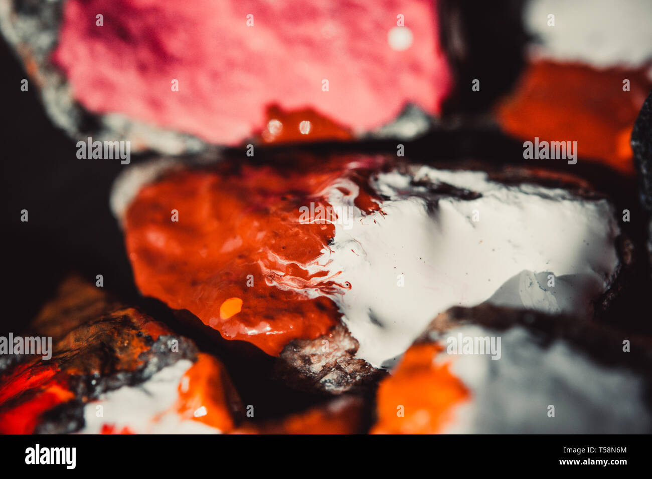 Peinture Peinture colorée se répand à la surface de petites pierres close-up, macro Banque D'Images