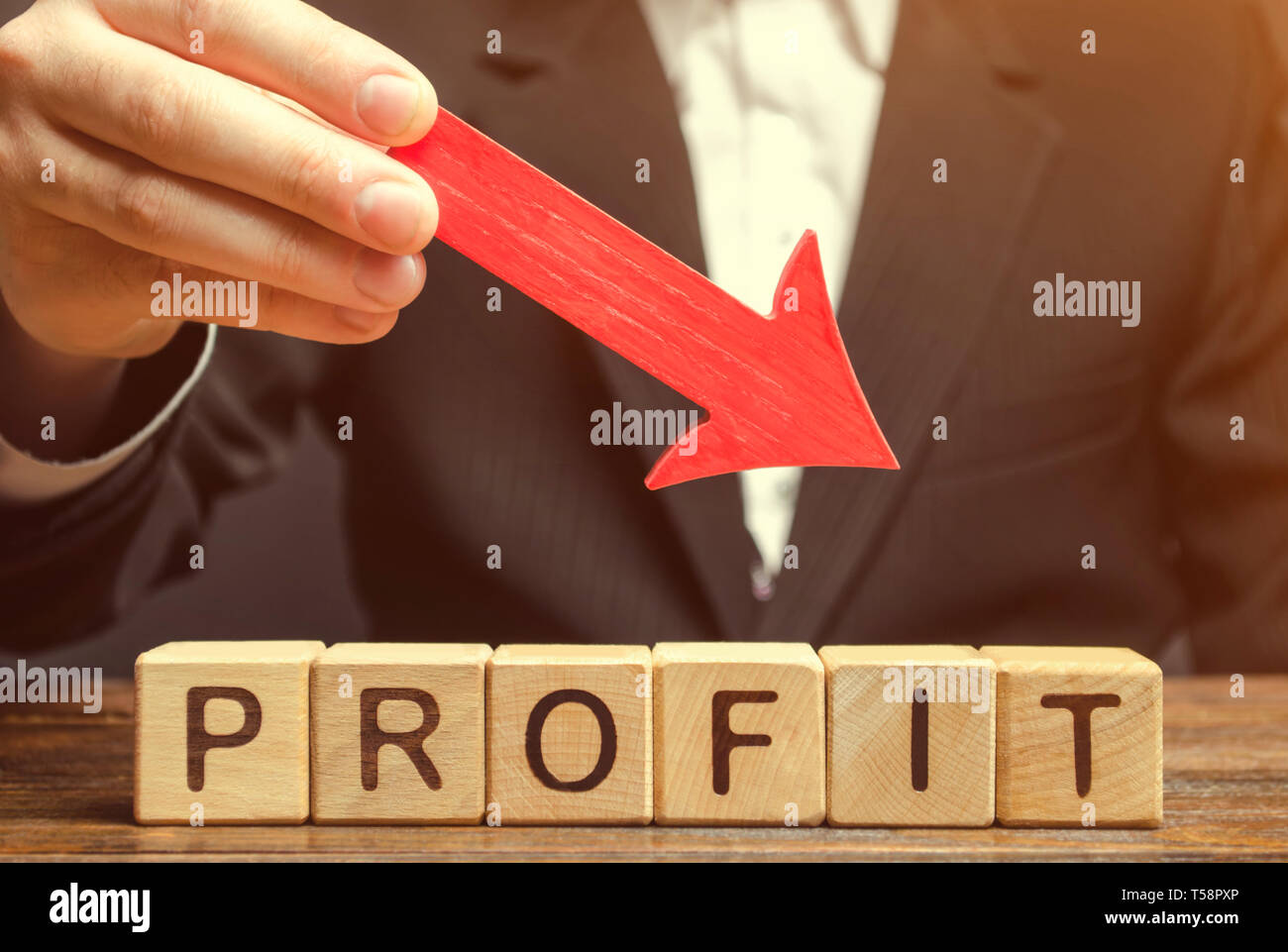 Un homme d'affaires est tenant une flèche rouge sur des blocs de bois avec le mot profit. L'entreprise échoue. La perte de l'investissement. Les faibles. Petit revenu Banque D'Images
