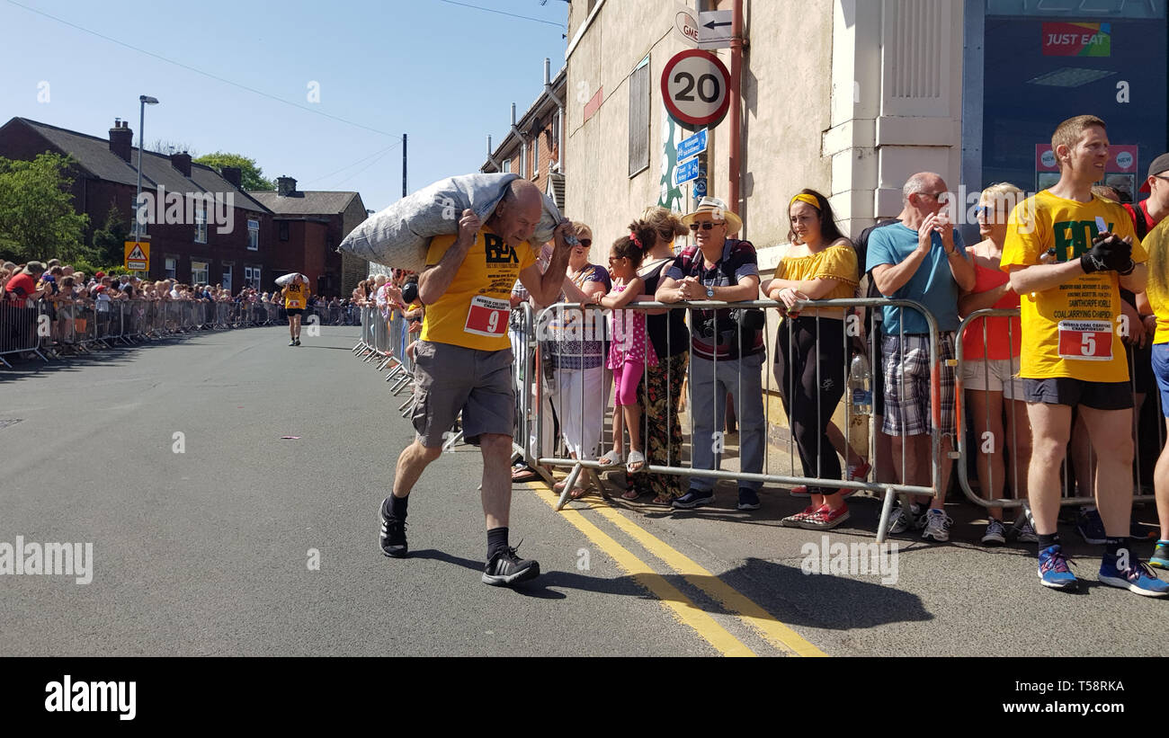 David Page, 72 (à droite), plus ancien jamais concurrent dans le monde, transportant du charbon, Championnats porte son 7er 50kg (12lb) en conditions étouffantes pour la banque traditionnelle maison de vacances dans l'événement Gawthorpe, West Yorkshire. Banque D'Images