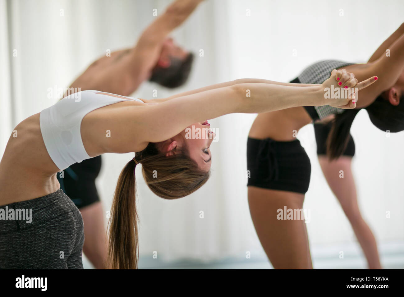 Jeune femme se concentre sur son posent alors qu'elle assiste à un cours de yoga. Banque D'Images