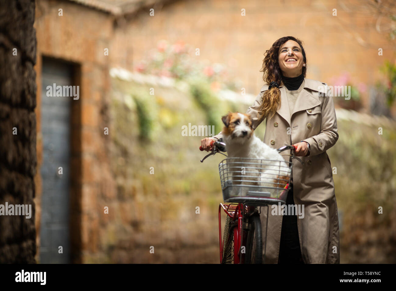 Happy young woman vélo avec un chien dans le panier. Banque D'Images