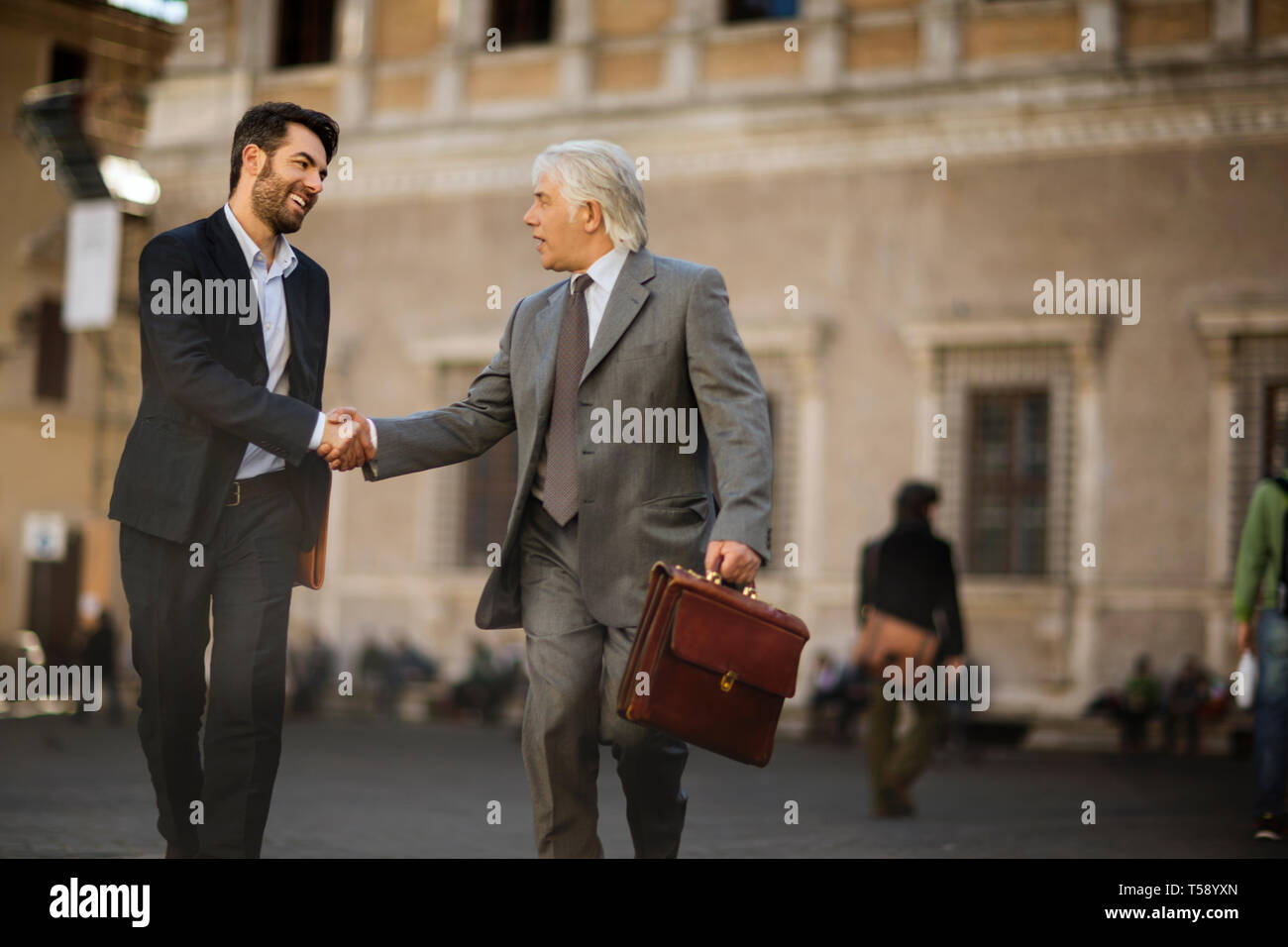 Mature businessman a une rencontre fortuite avec un jeune collègue, alors qu'ils sont dans la ville. Banque D'Images