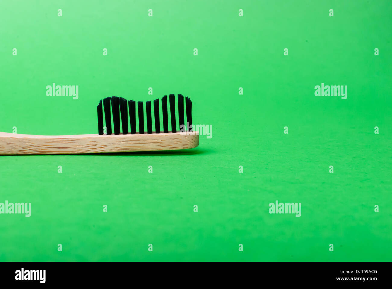 Close up Vue de côté de la tête d'une brosse à dents en bambou sur fond vert with copy space Banque D'Images