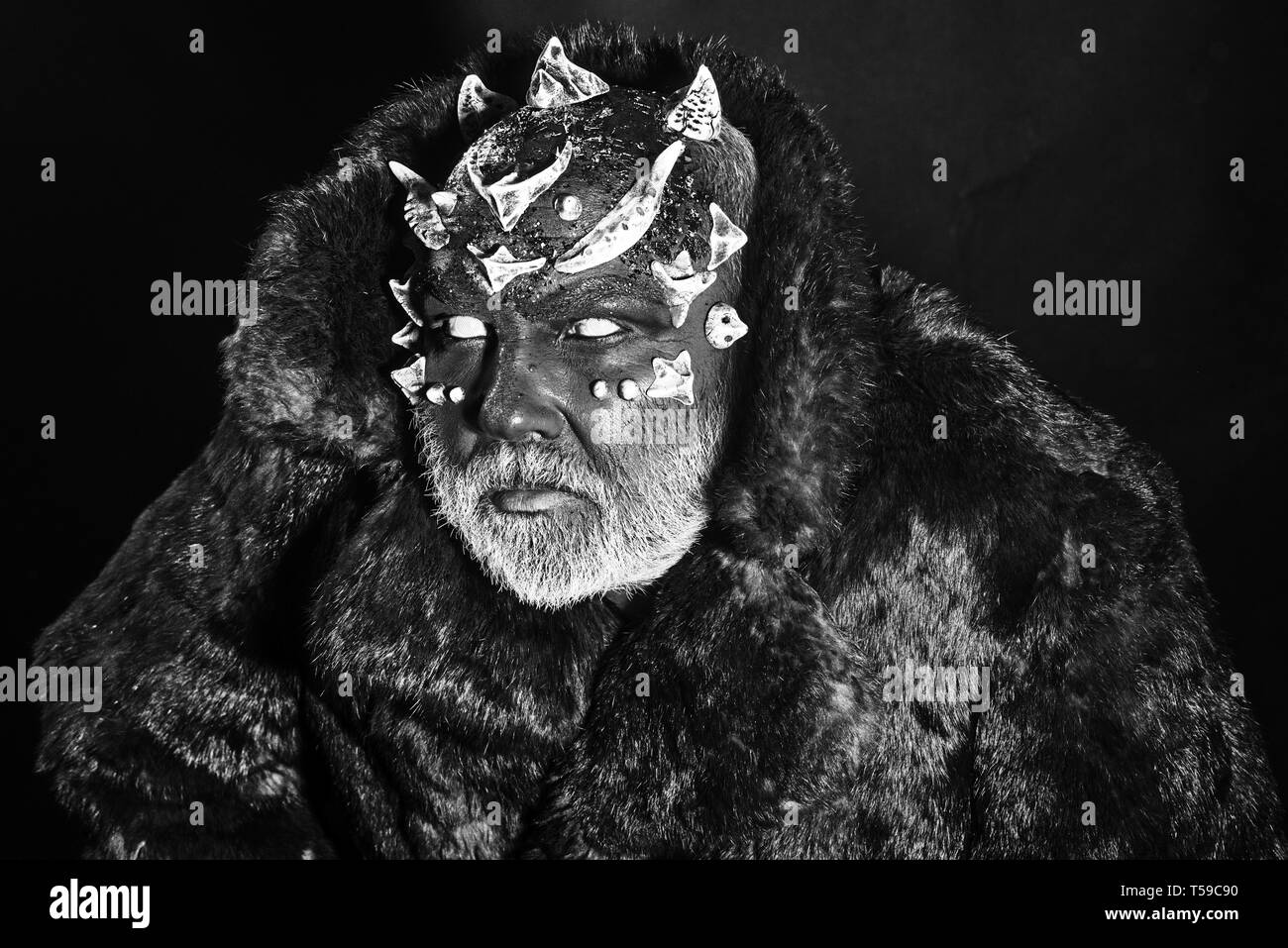 Man avec barbe blanche habillé comme Monster. Alien, démon, sorcier maquillage. Concept mal. Démon avec visage rouge sur fond noir, Close up. Man Banque D'Images