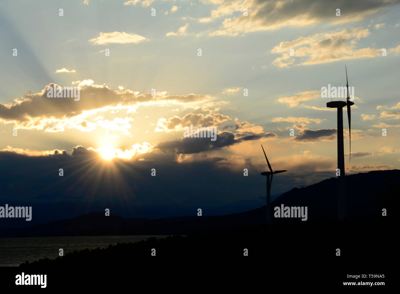 Silhouette sombre de l'énergie éolienne éoliennes sur la colline en face de ciel coucher de soleil nuageux spectaculaire, la production d'électricité respectueuse de l'environnement Banque D'Images
