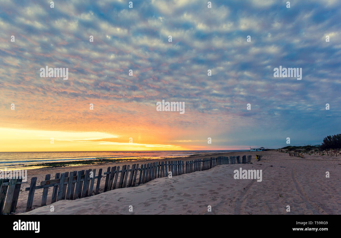 Clôture sur plage de sable fin au coucher du soleil à Chipiona, l'Andalousie. Des empreintes de pas dans le sable. Arrière-plan de voyages vacances Banque D'Images