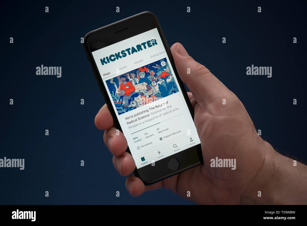 Un homme se penche sur son iPhone qui affiche le logo Kickstarter (usage éditorial uniquement). Banque D'Images