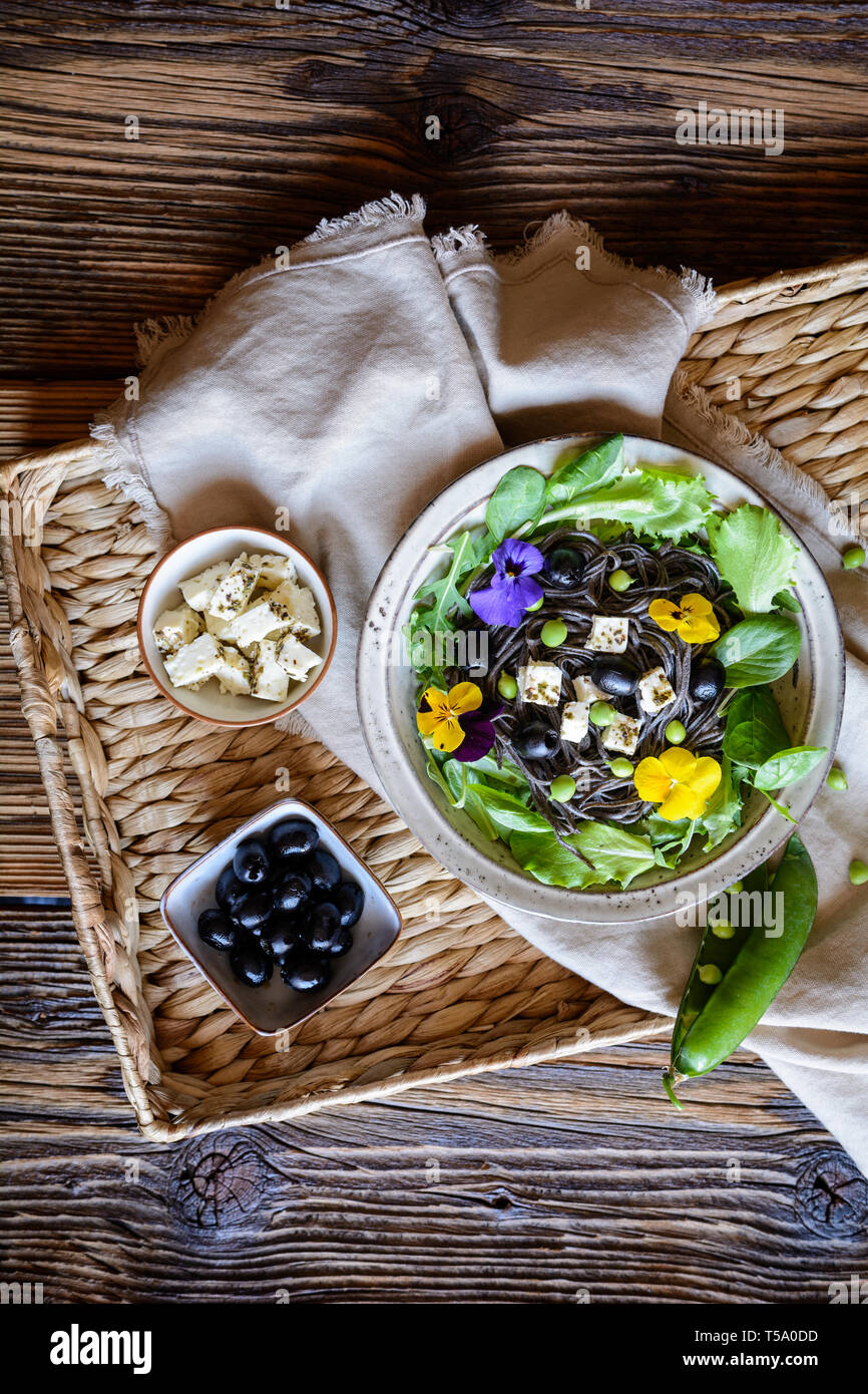 Haricots noirs végétarien salade de légumes verts, olives, petits pois, fromage de brebis, décoré avec des fleurs comestibles Banque D'Images