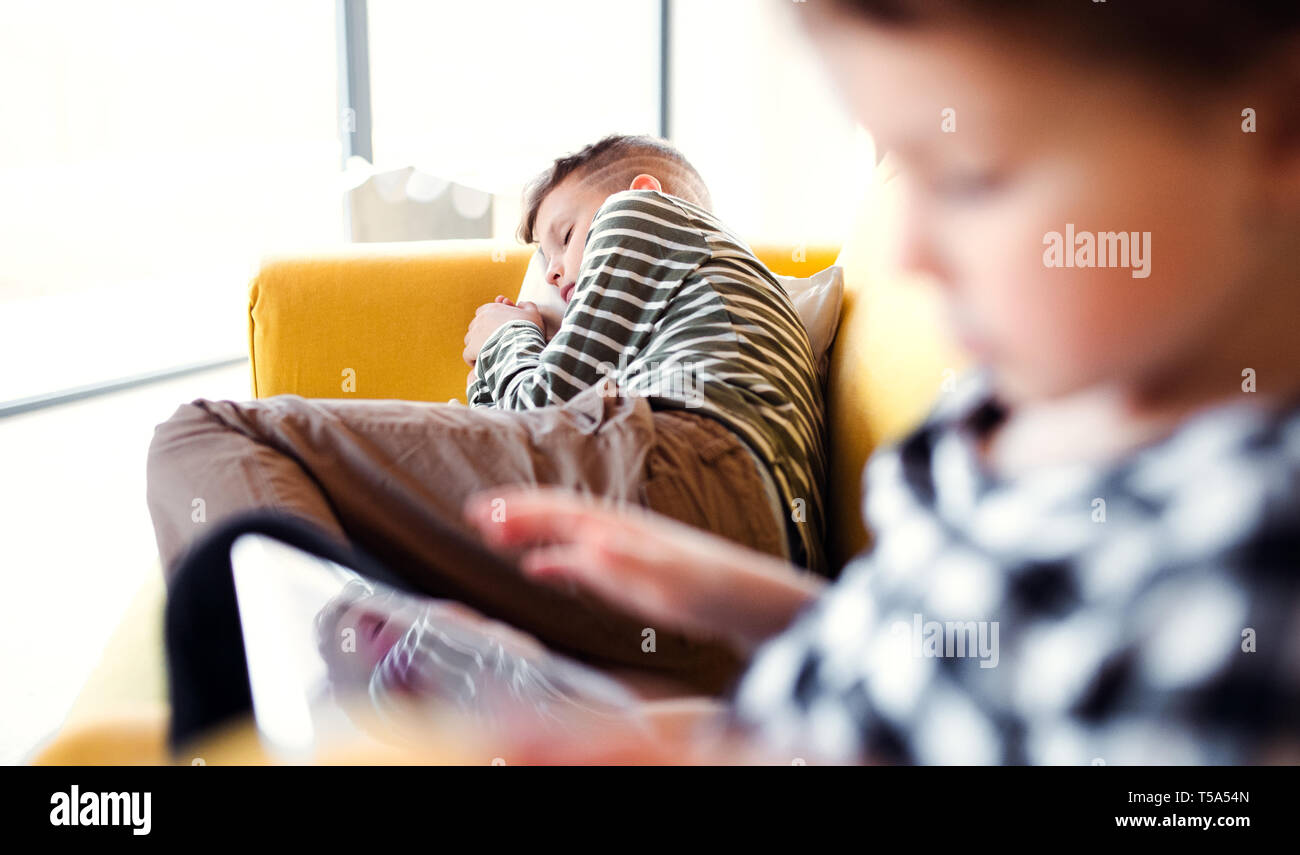 Deux enfants de passer du temps sur un canapé à l'intérieur à la maison. Banque D'Images