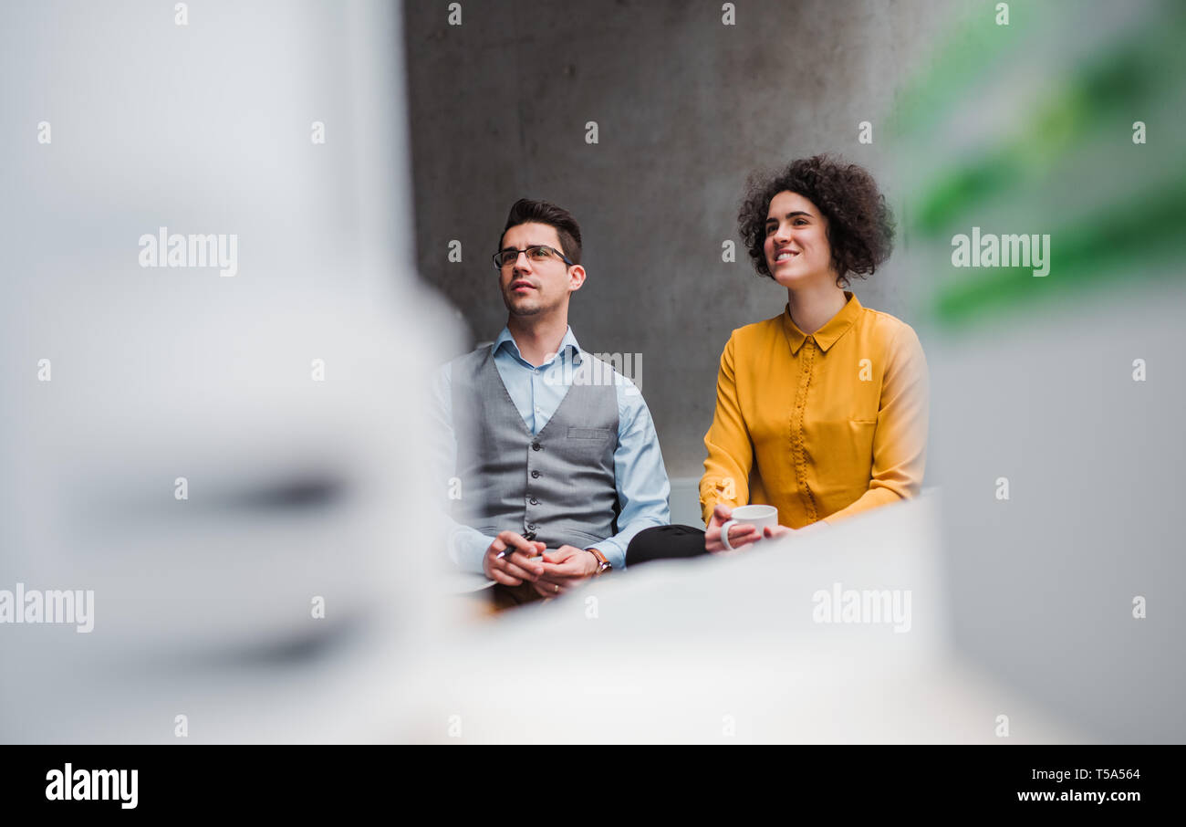 Deux jeunes businesspeople sitting in office, l'écoute d'une présentation. Copier l'espace. Banque D'Images