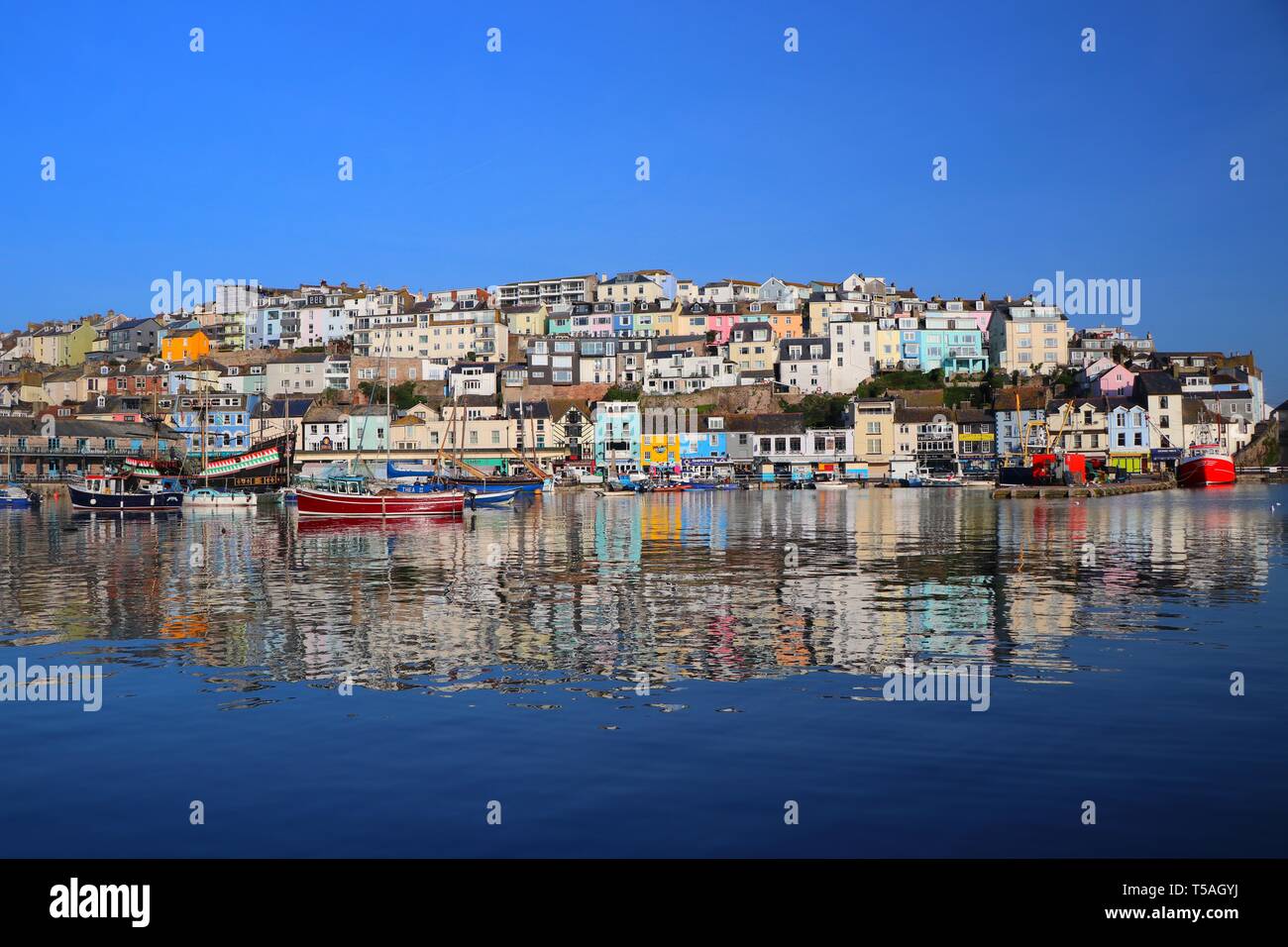 Ciel bleu vif au-dessus de la ville de Brixham, Devon, se reflète dans l'eau fixe du port à marée haute. Brixham Harbour, Devon, Royaume-Uni. Banque D'Images