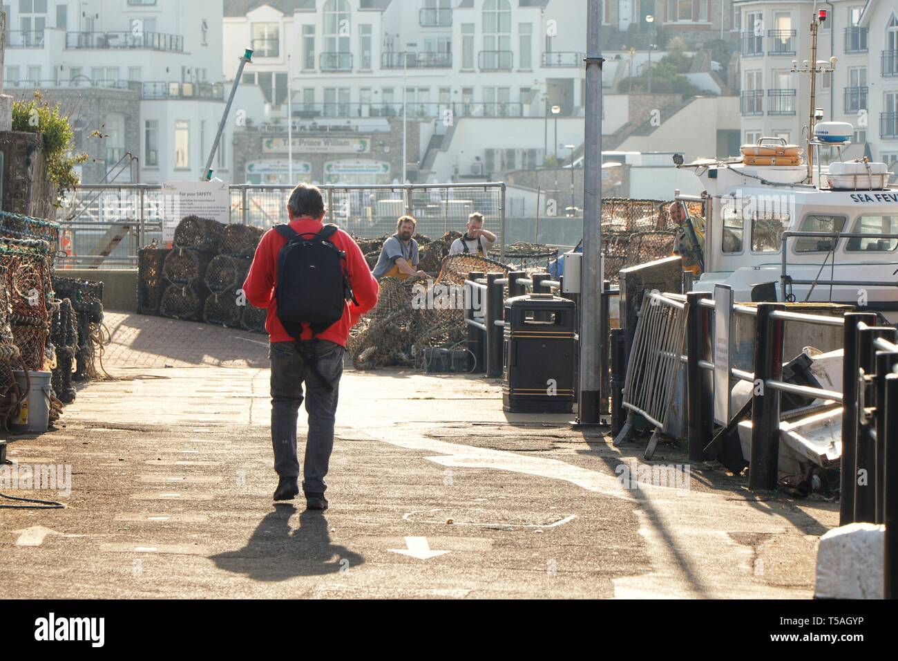 Un homme s'approche d'un groupe de pêcheurs préparent leurs filets par un beau matin, le port de Brixham, Devon, UK. Banque D'Images