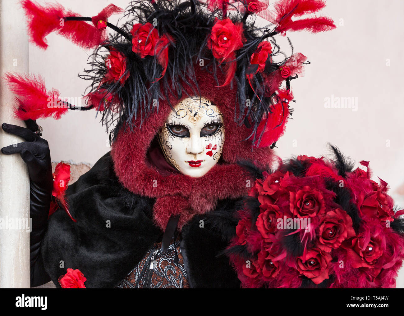 Personne au masque blanc et rouge costume noir tenue rose flowers, Carnaval de Venise, Italie Banque D'Images