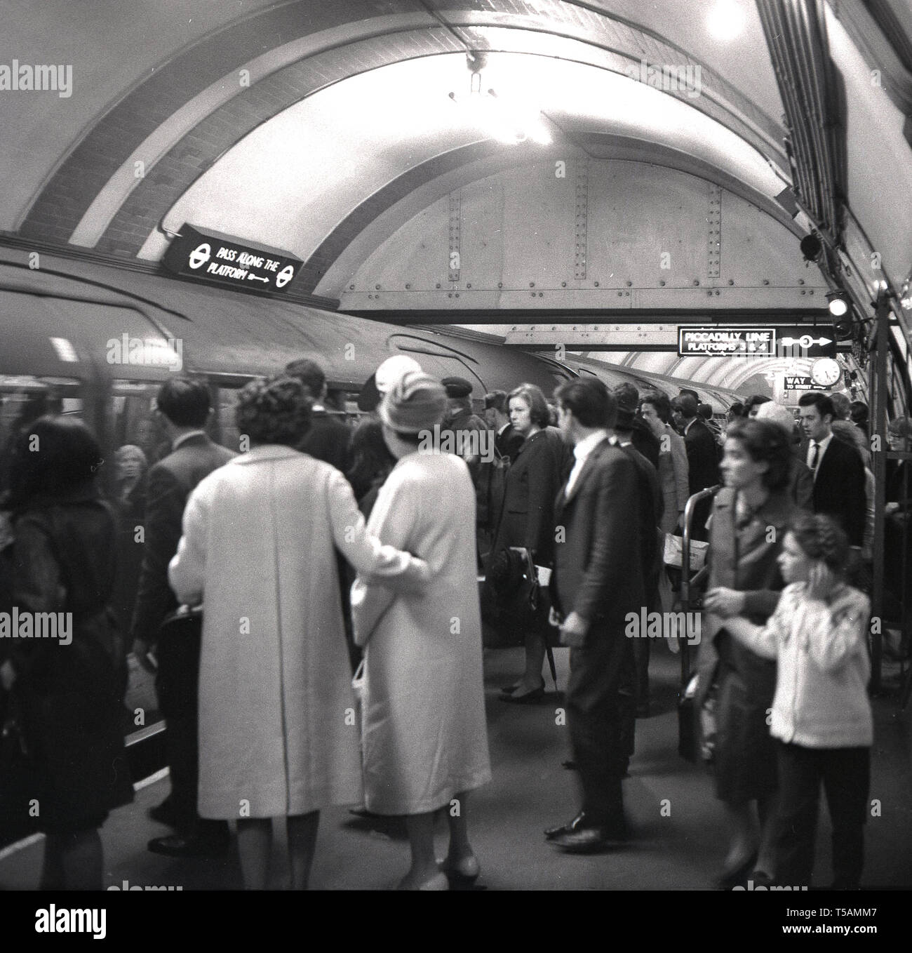 Années 1960, historiques, des passagers sur un platofrm bondé à propos à bord d'un train de tube sur le métro de Londres, Londres, Angleterre, Royaume-Uni. Banque D'Images