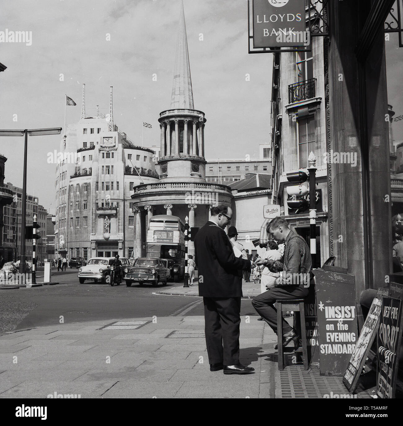 Années 1960, historiques, Marylebone, Londres, à l'extrémité nord de la rue Regent, un homme d'acheter le journal Evening Standard d'un vendeur assis sur un tabouret dans une banque Lloyds signe. La BBC Broadcasting House à Portland Place et All Souls Church à Langham Place également dans l'image, ainsi que les voitures de l'époque et un bus Routemaster n° 3 en direction de Crystal Palace. Banque D'Images