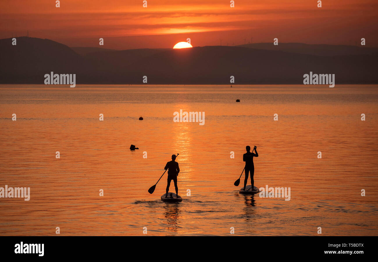 Le plus Paddleboarders le week-end de Pâques magnifique lever du soleil près du petit village de Mumbles près de Swansea ce matin que la région est baigné Banque D'Images