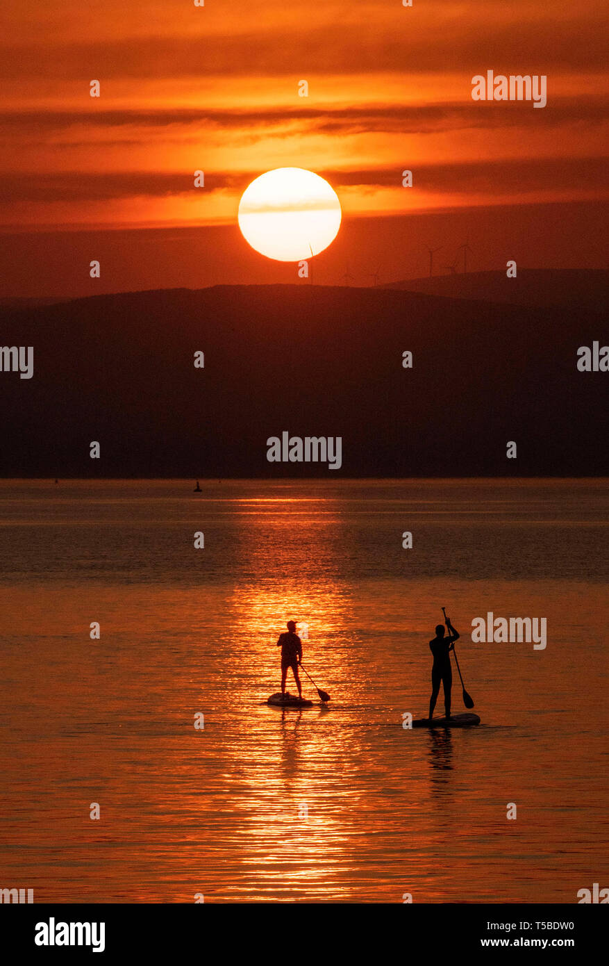 Le plus Paddleboarders le week-end de Pâques magnifique lever du soleil près du petit village de Mumbles près de Swansea ce matin que la région est baigné Banque D'Images