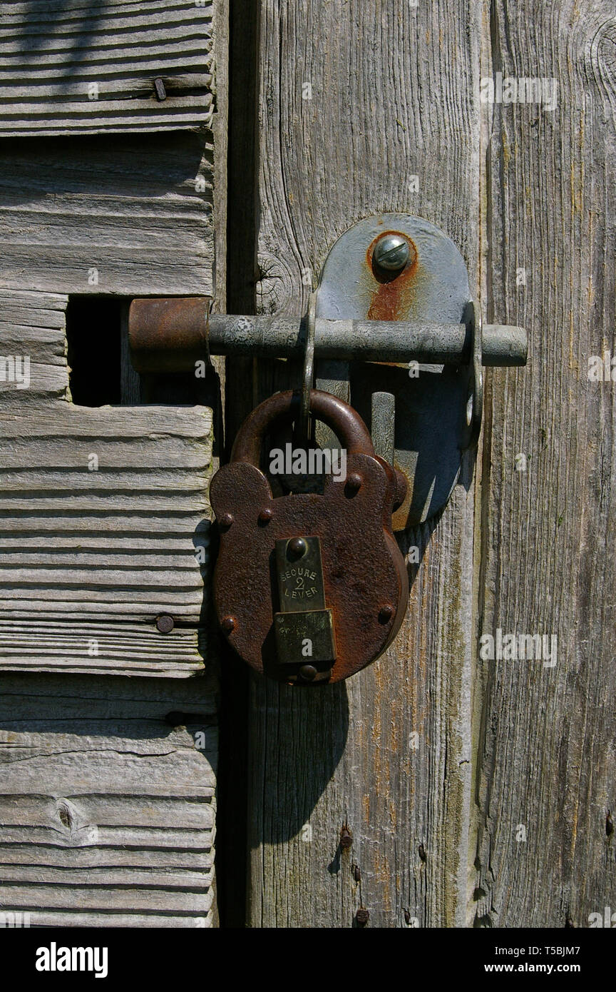 Close up d'un boulon et d'un cadenas sur le bois patiné d'un vieux hangar, UK Banque D'Images