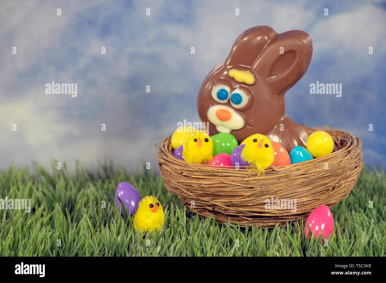 Lapin de Pâques en chocolat et jaune avec des poussins oeufs dans le nid d'herbes Banque D'Images