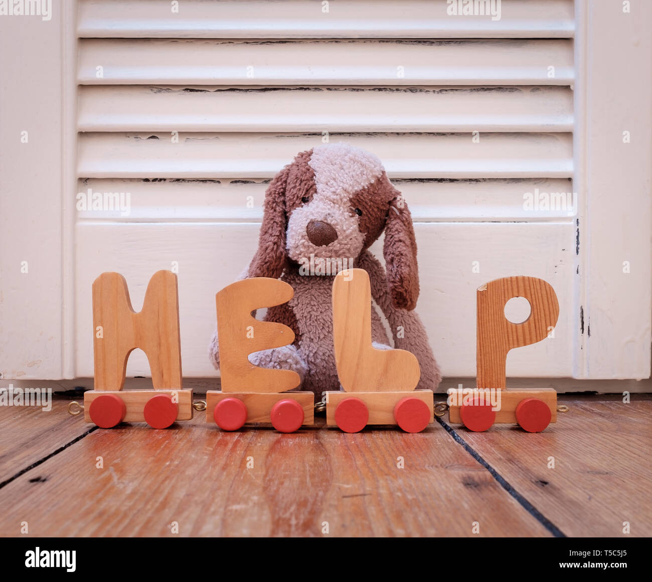 Cuddly chien poilu brun jouet et lettres qui le mot HELP. Concept pour les enfants dans le besoin Banque D'Images