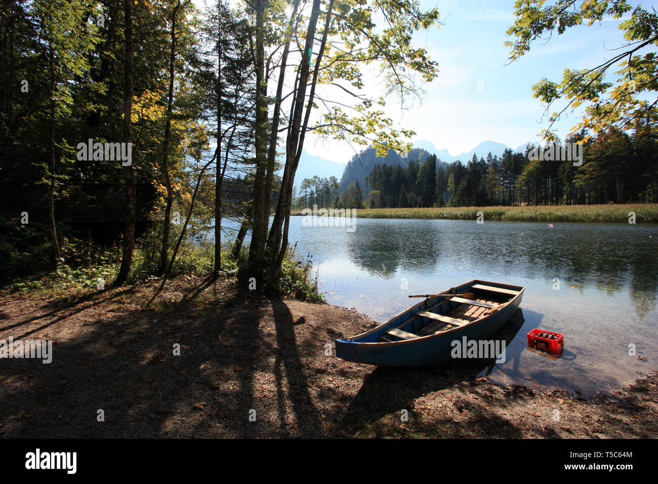 Barque en bois sur la côte à côté d'une caisse de bière rouge dans l'eau froide du Almsee, près de Grünau im Almtal, Autriche Banque D'Images