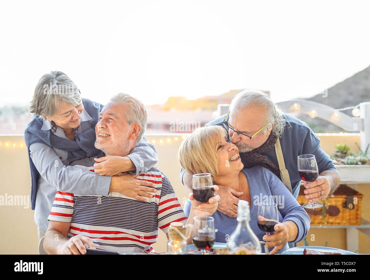 Happy friends having fun boire du vin rouge en terrasse en plein air - les personnes âgées de dîner et rire ensemble Banque D'Images