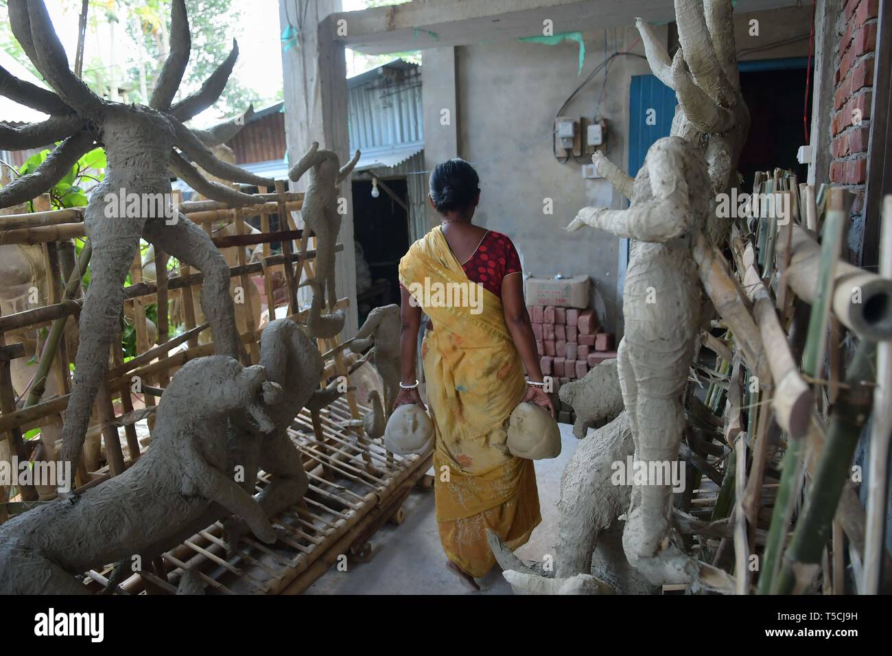 Un artisan, ajoute à la face de l'argile une idole de la déesse hindoue Durga avant la prochaine fête hindoue Durga Banque D'Images