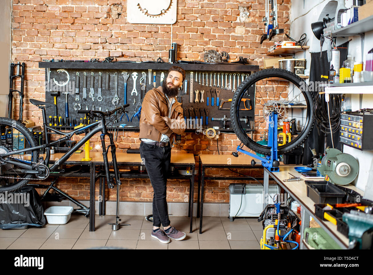 Portrait d'un jeune homme élégant qu'un propriétaire de boutique debout à l'atelier de vélo Banque D'Images