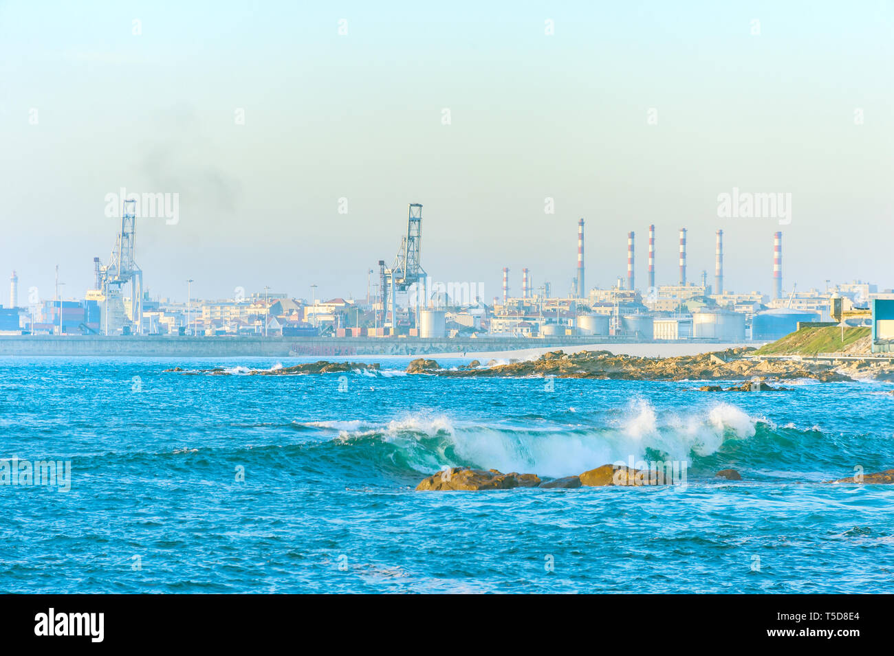 Les tuyaux de l'usine industrielle par la mer, des équipements portuaires, des grues, des vagues à terre brеak dans la lumière du soleil, Porto, Portugal Banque D'Images