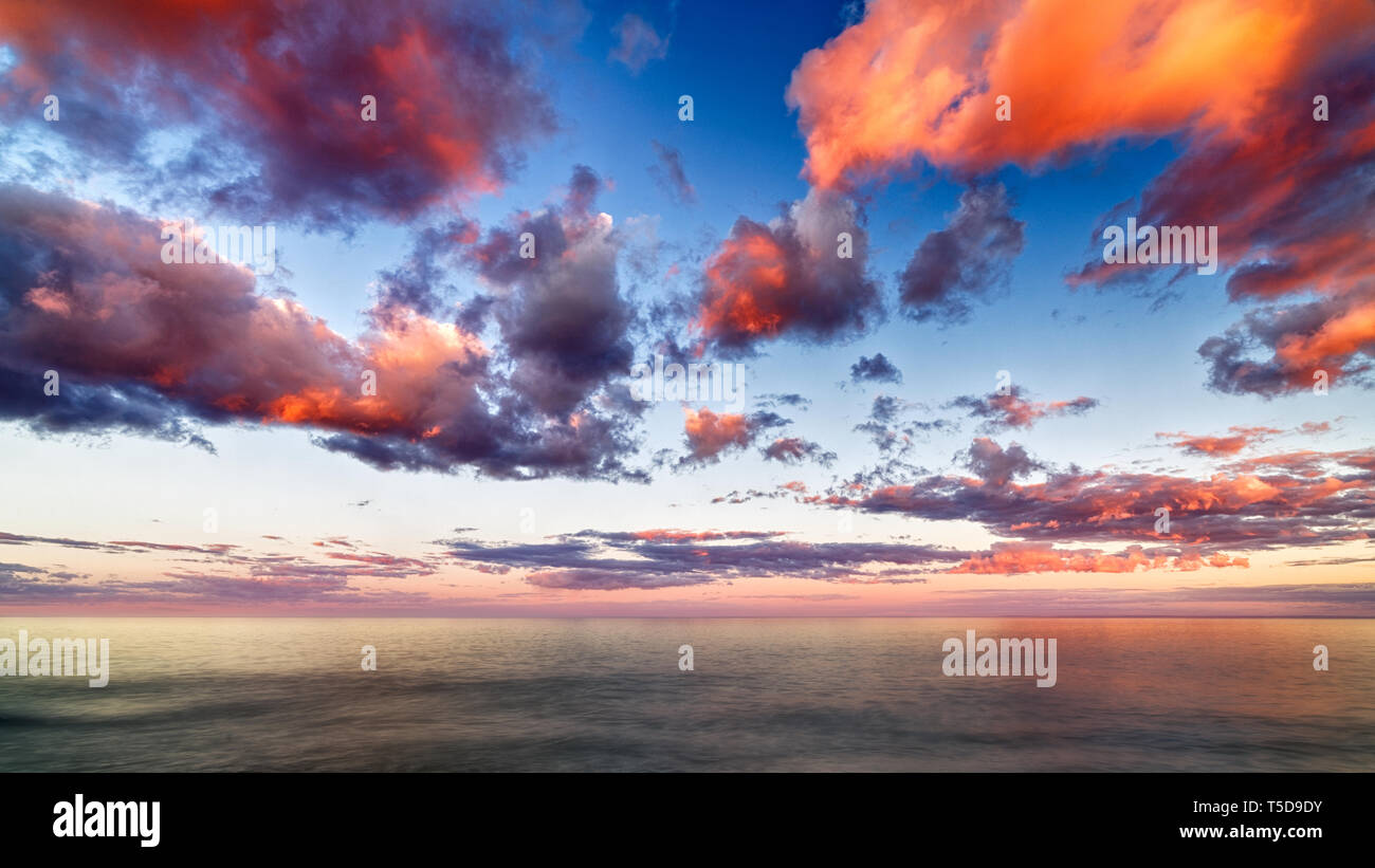 Beau coucher de soleil nuages sur le lac d'Horizon avec réflexions Banque D'Images