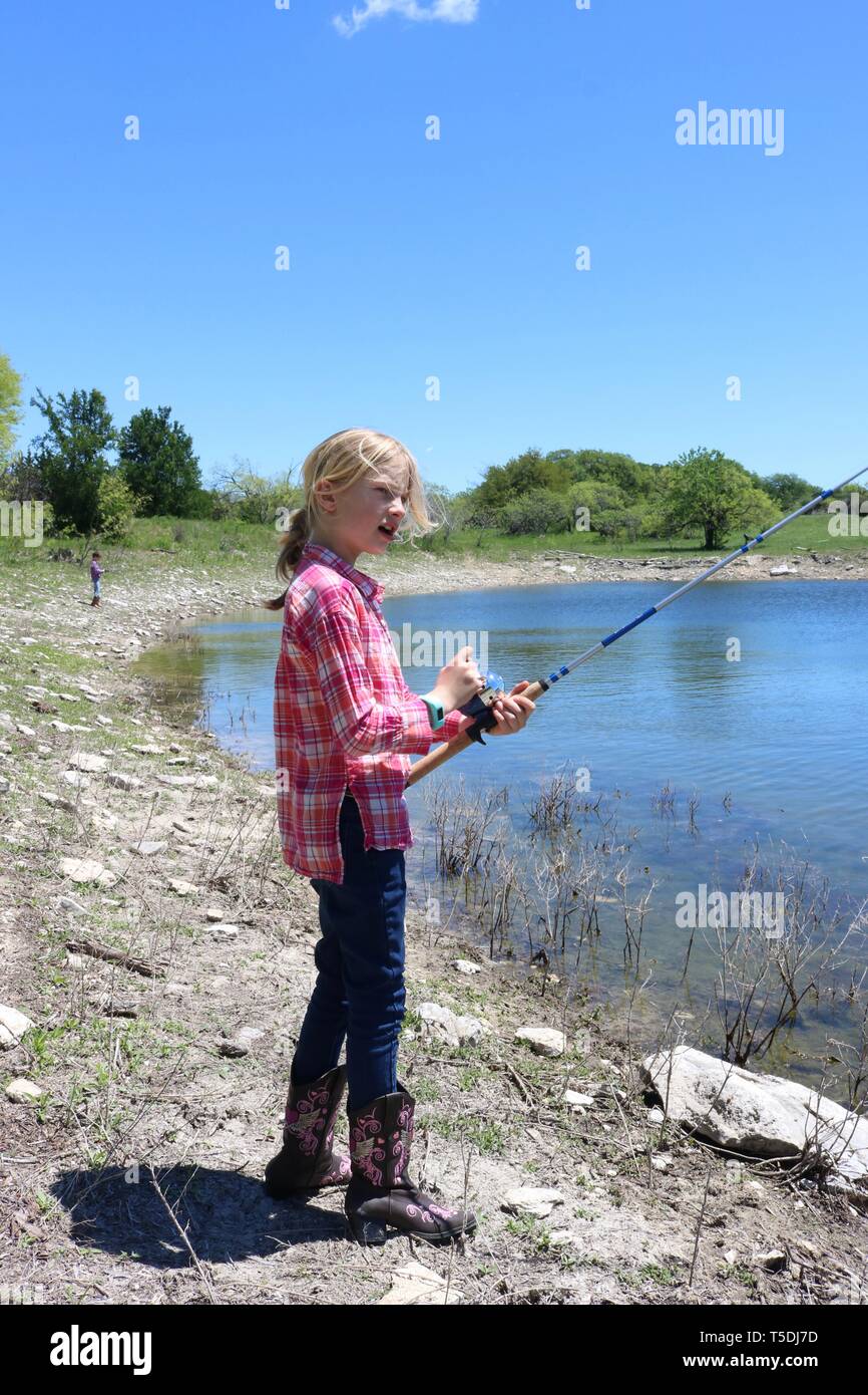 Pêche à la fille blonde au bord d'un trou d'eau Banque D'Images