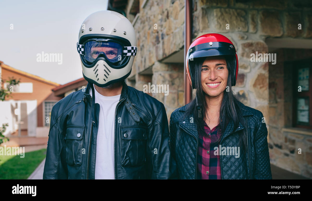 Jeune couple posant avec les casques de moto en plein air Banque D'Images
