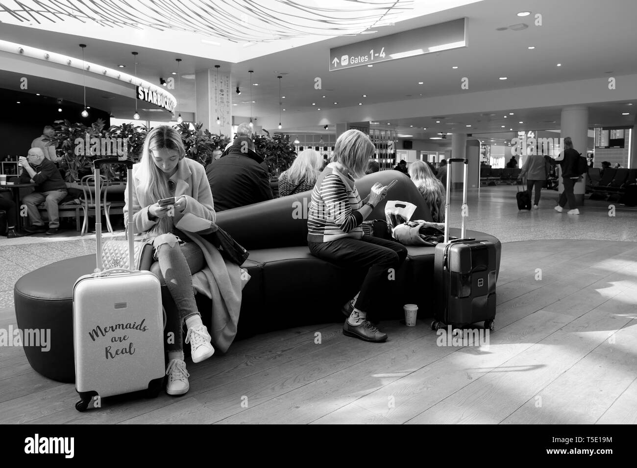 Les passagers en attente de vol siège dans la salle d'embarquement de l'aéroport avec une assurance looking at mobile phone texting UK KATHY DEWITT Banque D'Images Les passagers en attente de vol siège dans la salle d'embarquement de l'aéroport avec une assurance looking at mobile phone texting UK KATHY DEWITT Banque D'Images