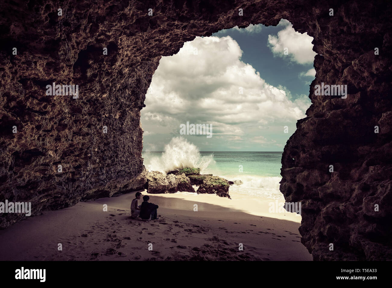 Quelques adultes indonésiens s'asseoir dans une caverne sur la plage tropicale sur fond de paysage nature paysage island Bali, Indonésie Banque D'Images