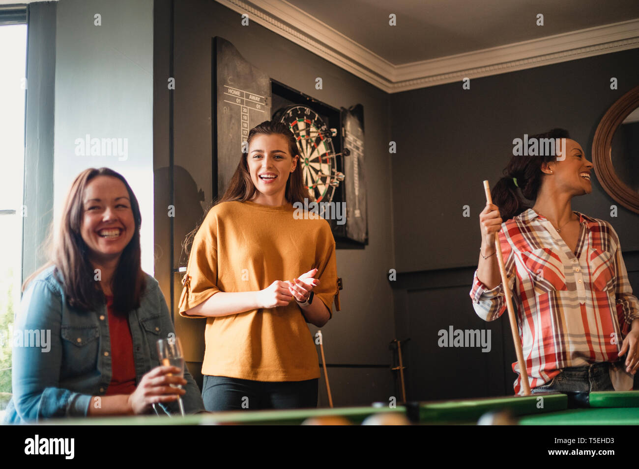 Petit groupe d'amies de jouer à un jeu de billard dans une salle de jeux dans une maison. Banque D'Images
