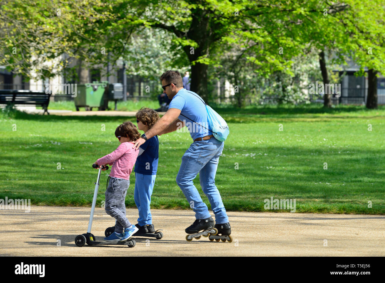 Père et fils sur des patins et des scooters, Hyde Park, Londres, Royaume-Uni Banque D'Images