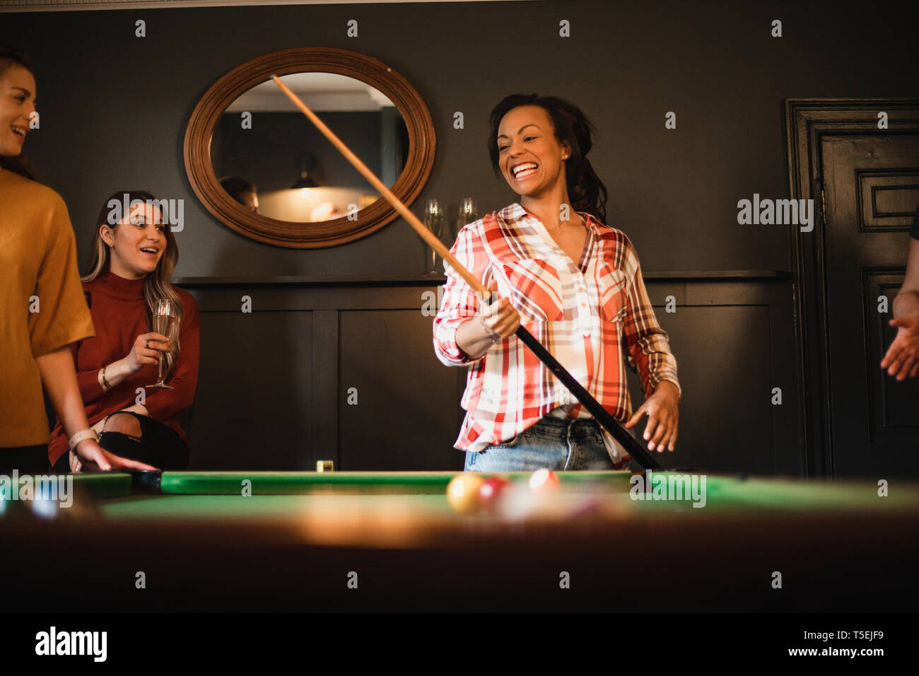 Petit groupe d'amies de jouer à un jeu de billard dans une salle de jeux dans une maison. Banque D'Images