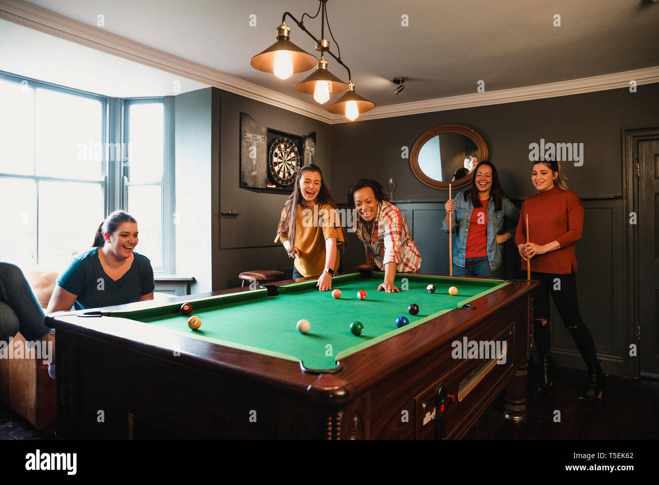 Petit groupe d'amis jouer au billard dans une salle de jeux dans une maison. Banque D'Images